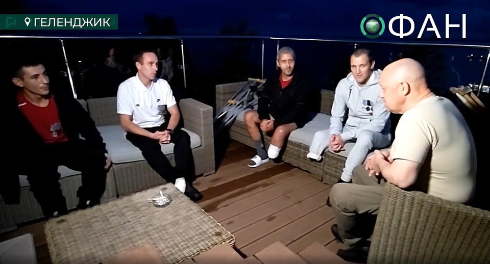 Jevgeni Prigozjin met vier ex-gedetineerden/veteranen op een dakterras.