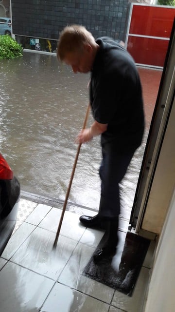 Stefaan probeert door te dweilen het water uit zijn huis te houden. 