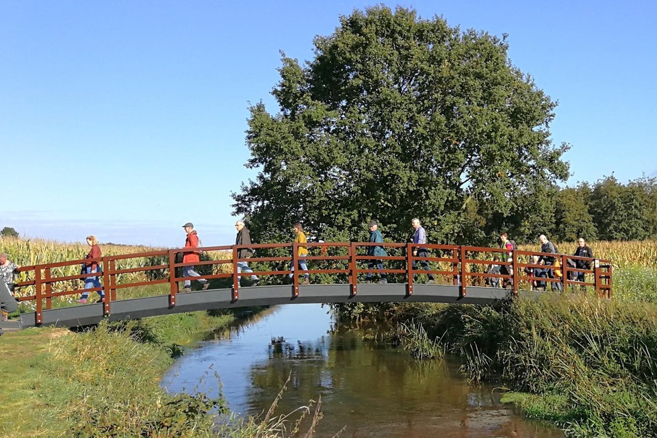 Een groep wandelaars loopt de fonkelnieuwe brug over de Aa in tijdens de Dag van de Trage Weg.