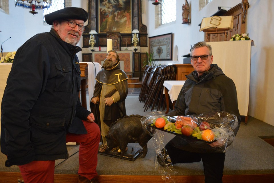 Burgemeester Johan De Ryck bij het beeld van Sint-Antonius met in zijn handen de marsepeinen varkenskop. Links de roeper van dienst.