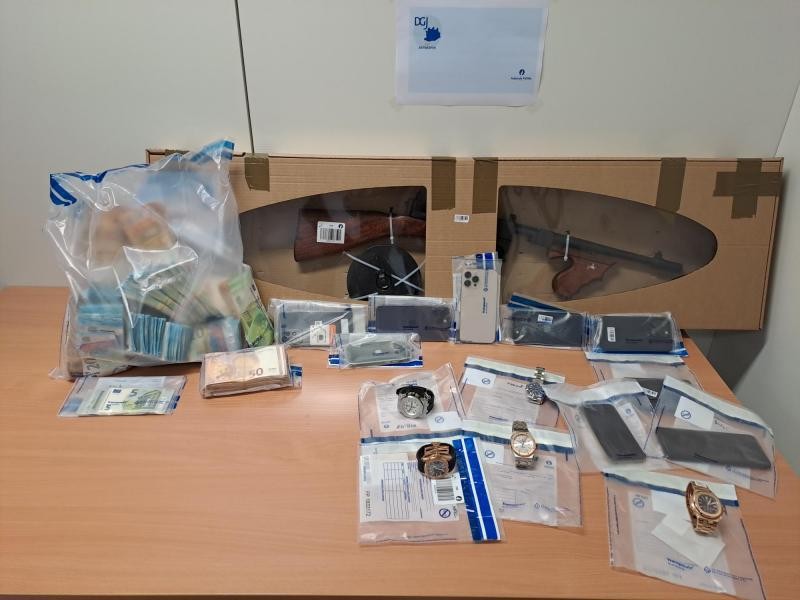 Tijdens de huiszoekingen werden meer dan 120.000 euro cash, telefoons, luxe horloges, een replica wapen en munitie in beslag genomen. 