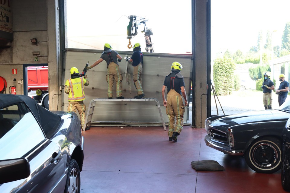 De brandweer moest de volledig beschadigde poort van de garage komen weghalen.
