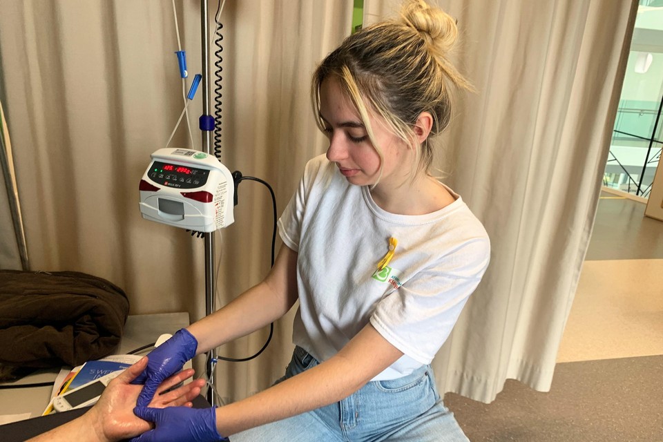 Chelsey geeft een handmassage aan een patiënt.