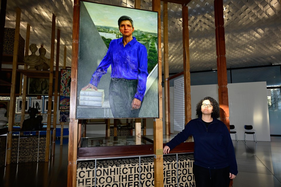 Kunstenares Naima Aouni poseert trots naast het portret van gouverneur Cathy Berx.