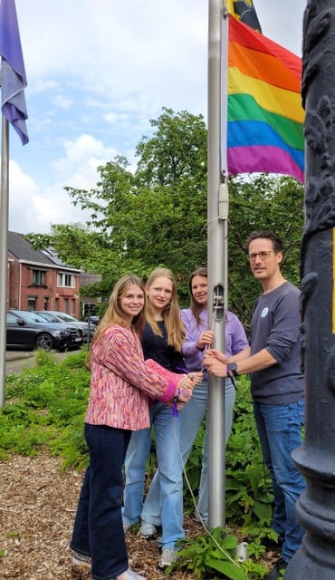 Leerlingen en burgemeester Dieter Wouters hijsen de regenboogvlag.