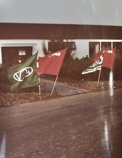 6 december 1991: de vlaggen van het ACV en ABVV wapperen in regen en wind aan de ingang van het houtbedrijf. 