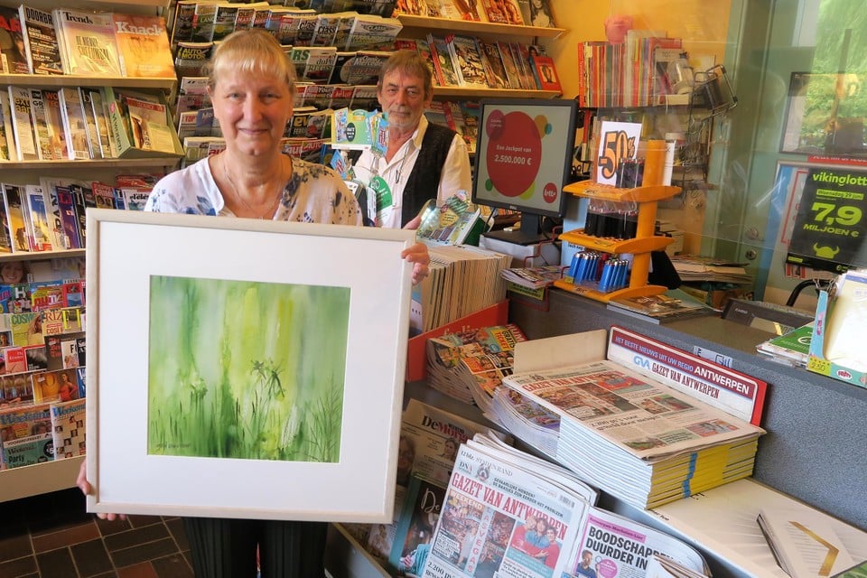 Ingrid toont één van haar bekroonde aquarellen. Voortaan zal ze hier schilderen in de plaats van Lotto-formulieren valideren en kranten verkopen. 