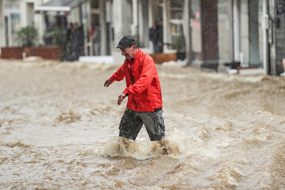 Een man baant zich een weg door het water in de straten van Spa. 