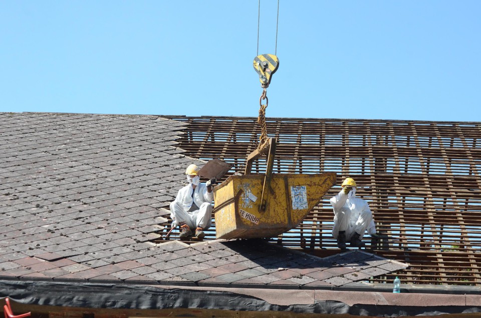 Voor de afbraak werden eerst de asbestleien van het dak een voor een verwijderd. 