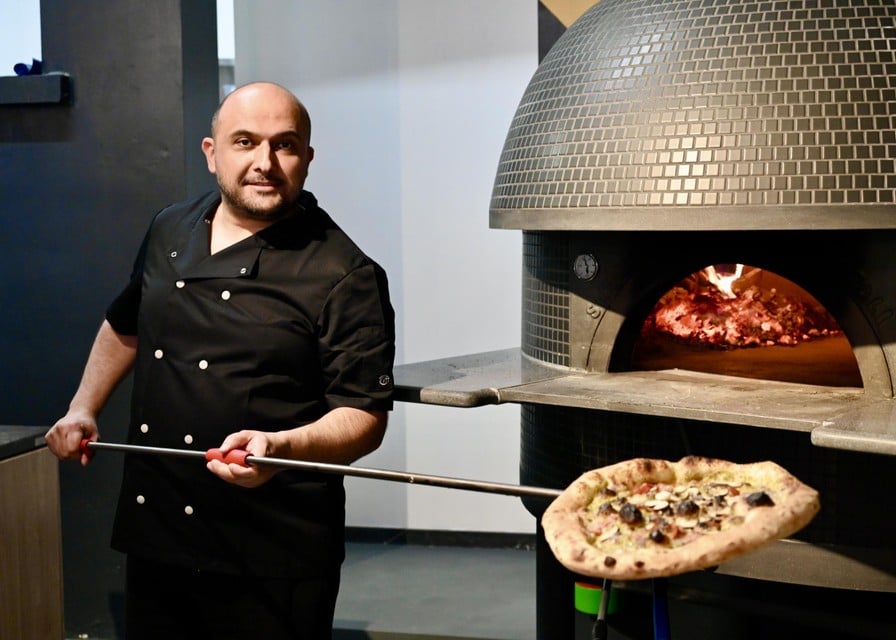 Hugo Ferreira haalt een pizza uit de houtoven.