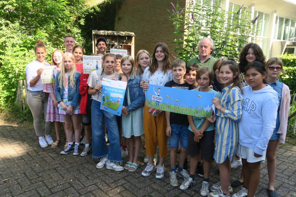 De zesde klas van juf Sien Delpiedsente met Bye Bye Gazon-ambassadeur Dieter Coppens en schepen Olivier Verhulst voor hun vijfsterren bijenhotel. 