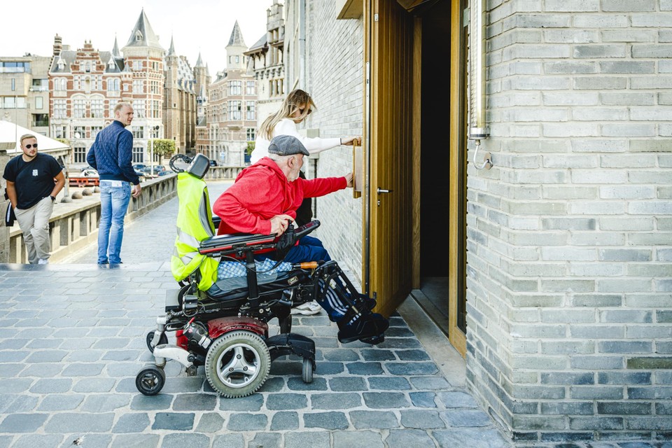 De zware deuren open trekken vanuit de rolstoel is niet eenvoudig. Gelukkig zijn er wel mensen die een handje willen helpen. 