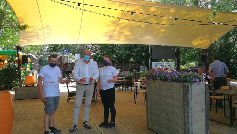 Toon Meeus en Jolien Sysmans helpen schepen Tom Corstjens (midden) een handje wanneer hij hun zomerbar De Ganzerik officieel opent.