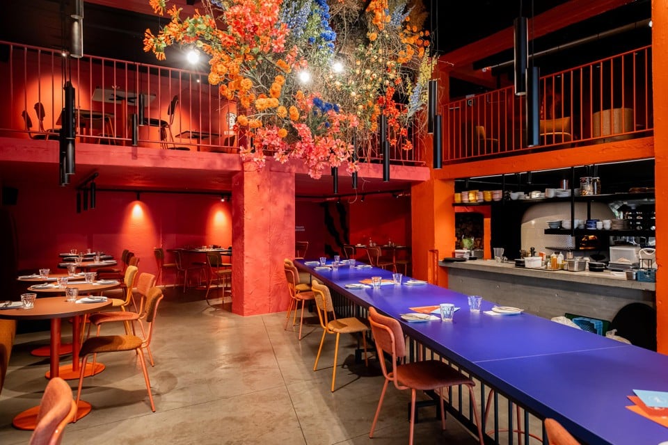 Qua interieur vallen de warme oranje en roze muren op, de op maat gemaakte knusse zetels, de blauwe lange tafel en natuurlijk ook het grote bloemstuk dat aan het plafond hangt.