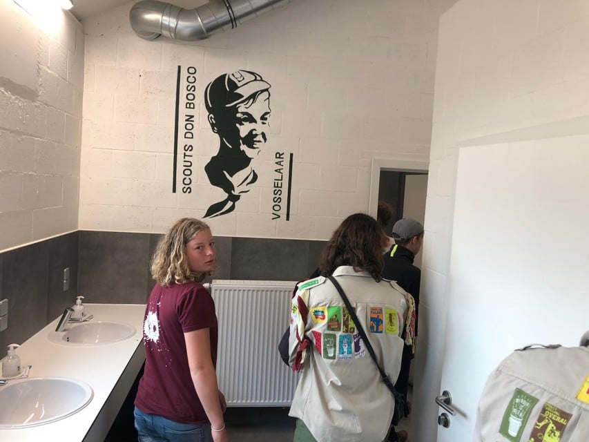 Groepsleiders Bertus Quatacker en Thijs Adriaensen knippen het lint van het nieuwe sanitair gebouw aan de scoutslokalen in Vosselaar door. 