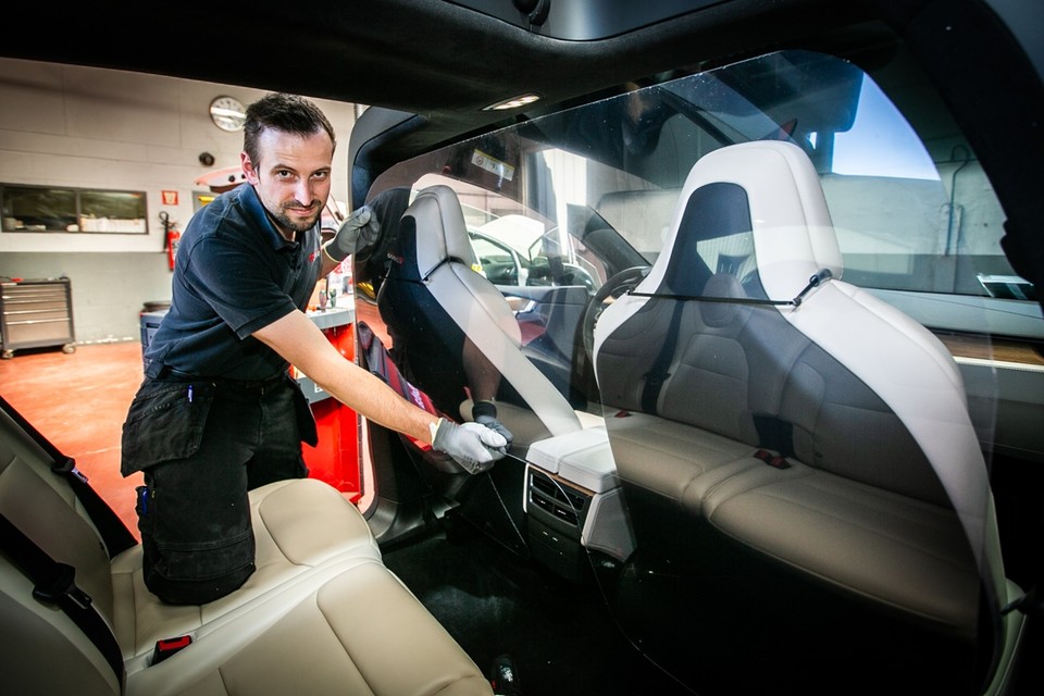 Dimas Van Rompaey toont hoe hij een plexiplaat in een taxi installeert.
