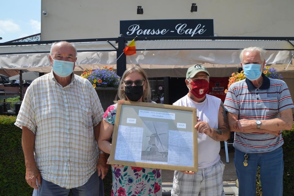 Sonja De Wolf van Pousse-Café met de ingelijste stichtingsakte van de Molekenskermis, te midden van haar klanten Neel, Frank en Johannes.