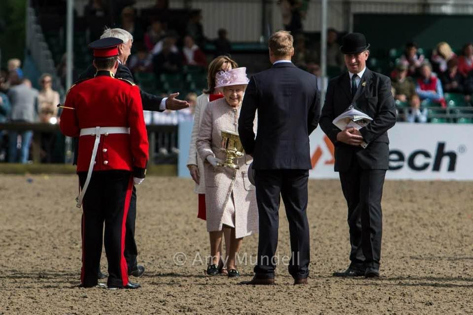 Menner Glenn Geerts ontvangt een beker uit handen van de Queen. 