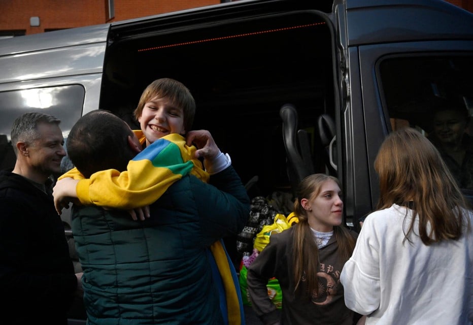 Een Oekraïense vader verwelkomt zijn drie kinderen nadat ze vastgehouden werden in Russisch bezet gebied.