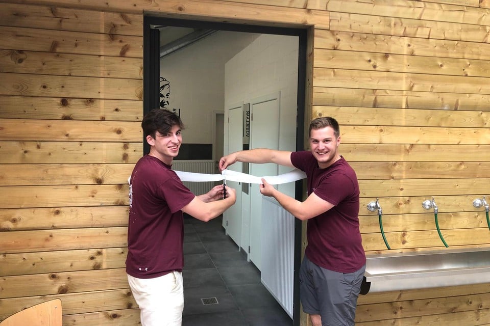 Groepsleiders Bertus Quatacker en Thijs Adriaensen knippen het lint van het nieuwe sanitair gebouw aan de scoutslokalen in Vosselaar door.