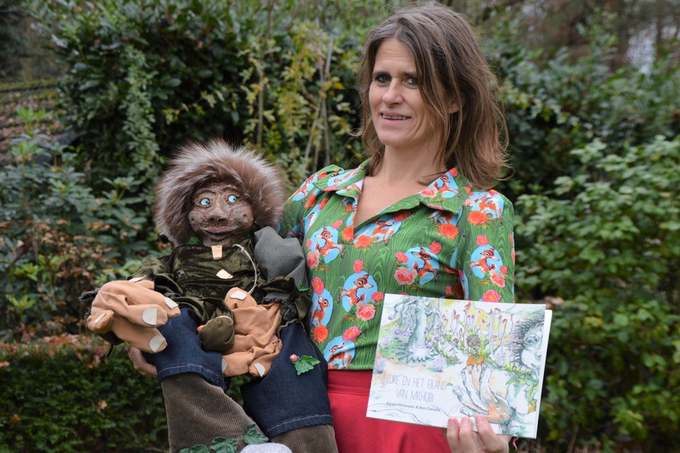 Karen Horemans met links de pop Michobi en rechts haar boek ‘Lore en het eiland van Michobi’.