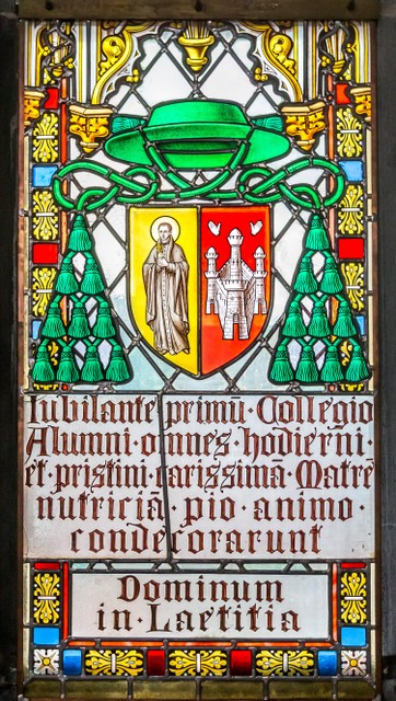Een opschrift op een glasraam dat verwijst naar de heilige Jan Berchmans en naar Antwerpen.  