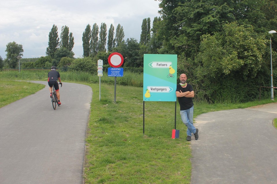 Bert aan het bord dat de gemeente vorige week plaatste. Links het pad naar de Scheldedijk, rechts de weg naar het centrum van Rupelmonde en het café van Bert.