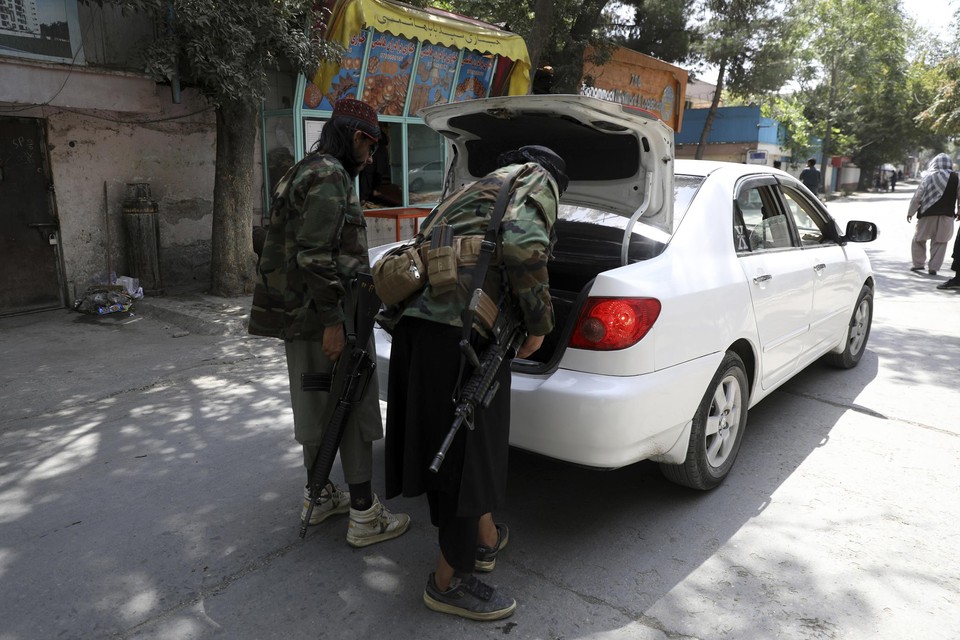 Talibanstrijders doorzoeken een auto aan een checkpoint. Vandaag werd ook een bus met passagiers voor de Belgische vluchten tegengehouden. 