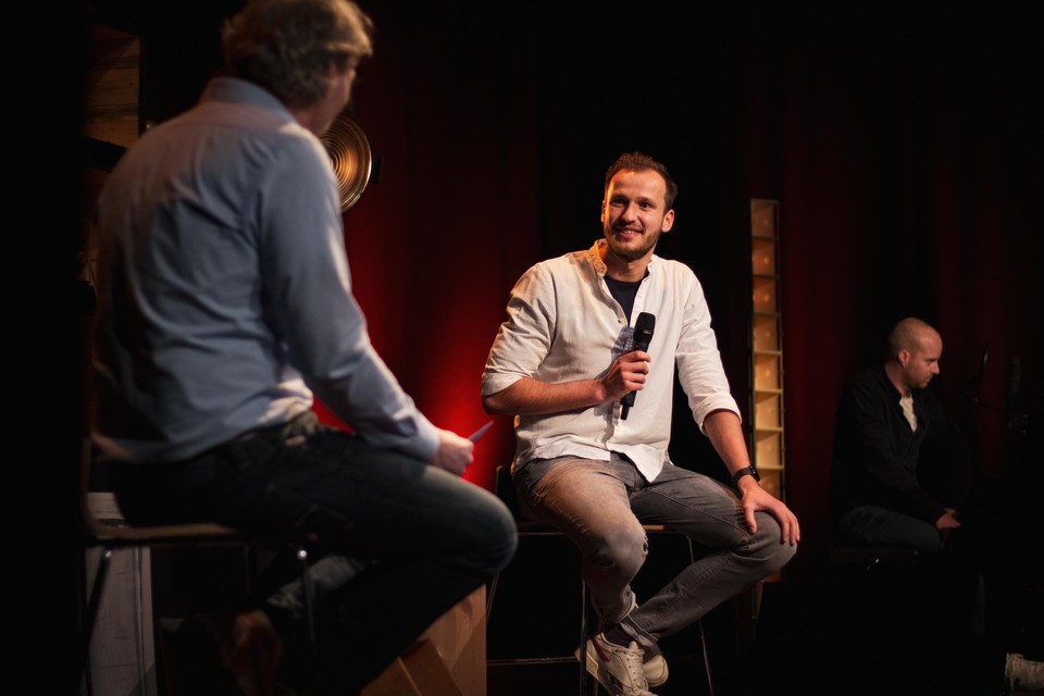 Patrick Poppe interviewt Michiel De Meyer met op de achtergrond muzikant Martijn Claes, waarmee Michiel een volgend muzikaal project aanvat.