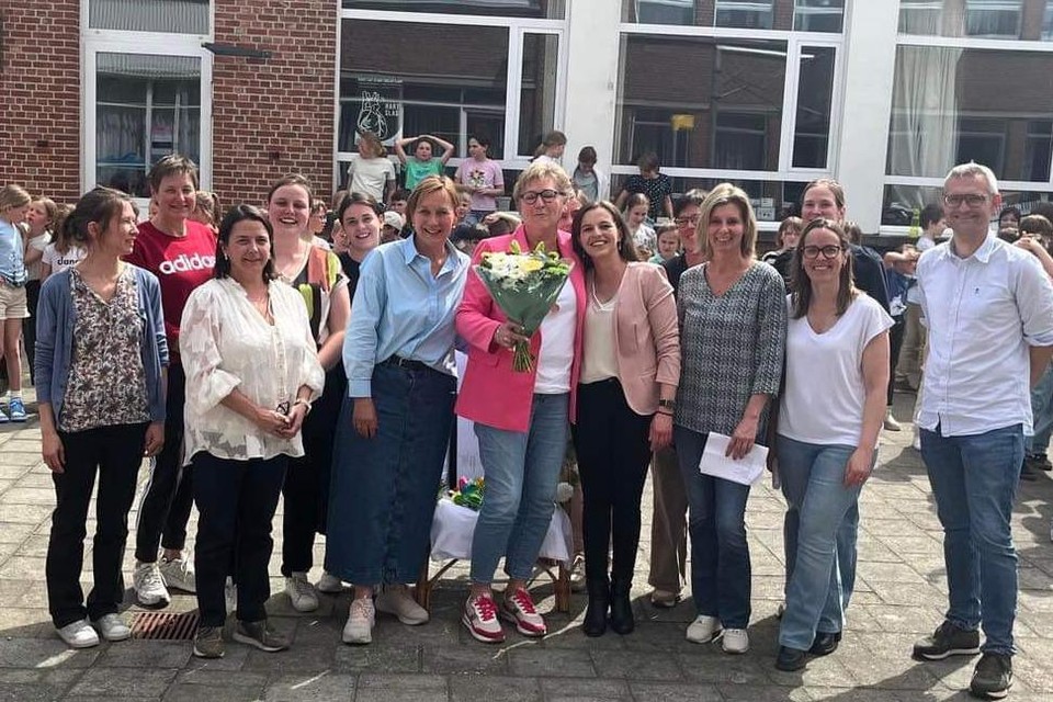 Juf Mia De Peuter (met bloemen) is omringd door directeur Els Renders (links van haar) en haar andere collega’s van vrije basisschool De Springplank in Lille.