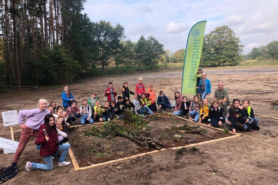De leerlingen van het vijfde leerjaar van ‘t Klavernest staan bij het natuurschilderij dat de jongens hebben gemaakt in de Visbeekvallei in Wechelderzande.