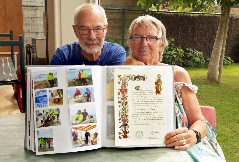 Fier tonen Pierre en Christiane hun plakboek met rechts de oorkonde die ze in Santiago de Compostella ontvingen. 