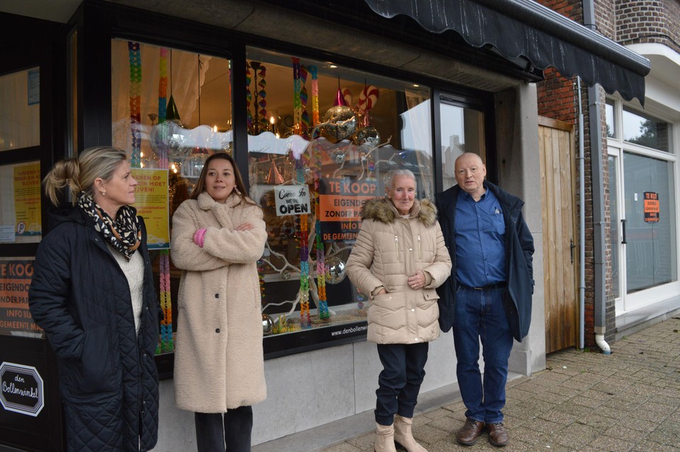 Enkele ondernemers en bewoonster Carry aan een vitrine met affiches.