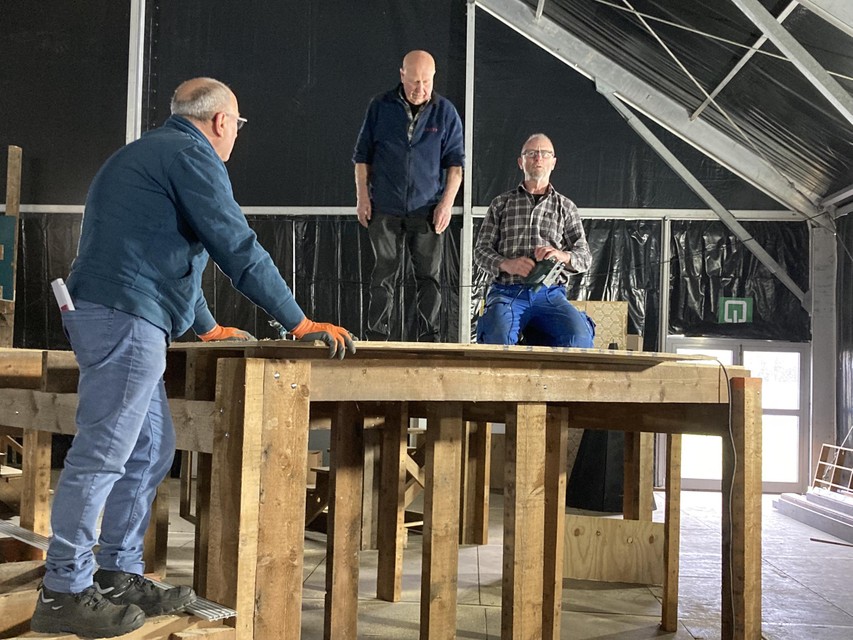 In de grote tent wordt met man en macht gewerkt aan het immense podium.
