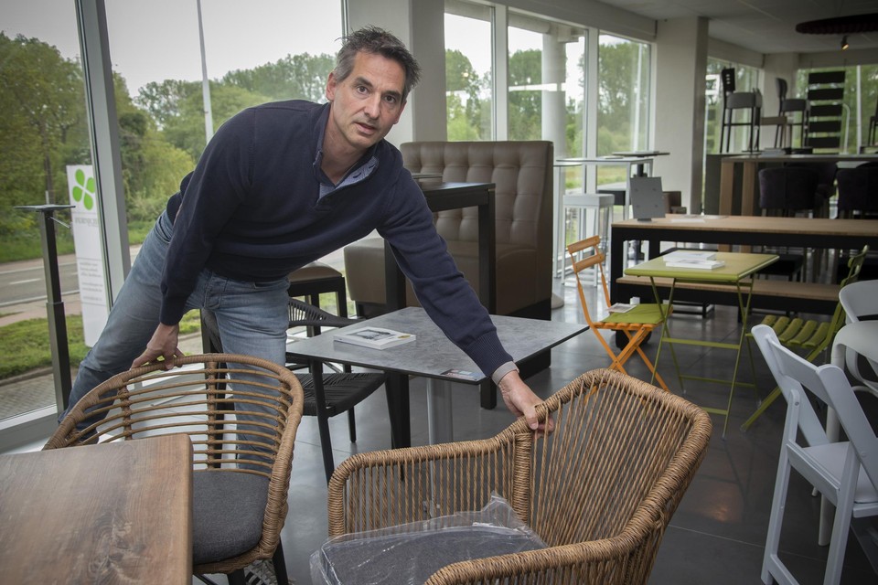 Tony schikt in de showroom enkele stoelen rond een tafeltje.