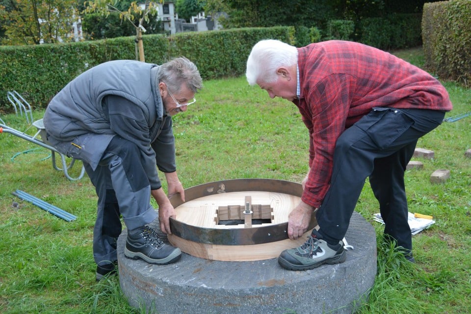 Louis De Pooter van de smedersgilde, rechts en Jan Nys van de Brakken (links) passen de ring vooraleer hem warmgestookt over de olmen ringen te kloppen.