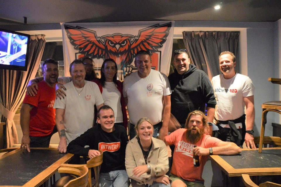 Enkele leden van ASC Rood Wit Legioen voor de vlag met bosuil van de RAFC-supportersclub in café De Patriot in Zandhoven. Tweede van links voorzitter François Nooytens en centraal cafébaas Rudi Bru.