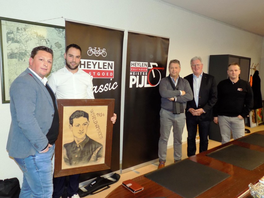 De organisatoren van de Heistse Pijl staan bij burgemeester Gilles Bultinck (CD&V). Hij toont een schilderij van Karel Kaers, de Vosselaarse wereldkampioen wielrennen in 1934.