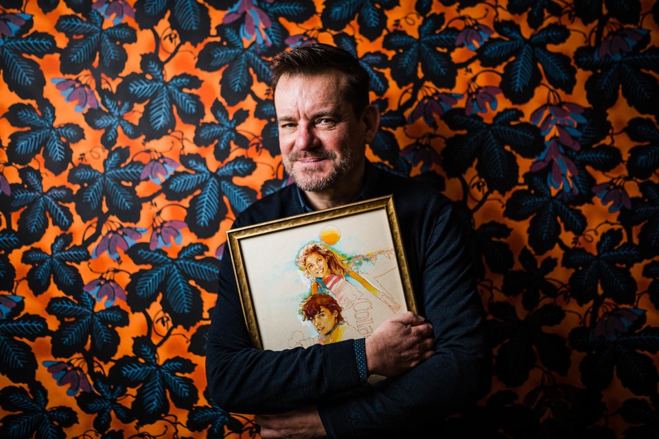 Schrijver Bart Moeyaert houdt een lijst vast met daarin de oorspronkelijke omslagillustratie van Duet met valse noten, van de hand van André Sollie.