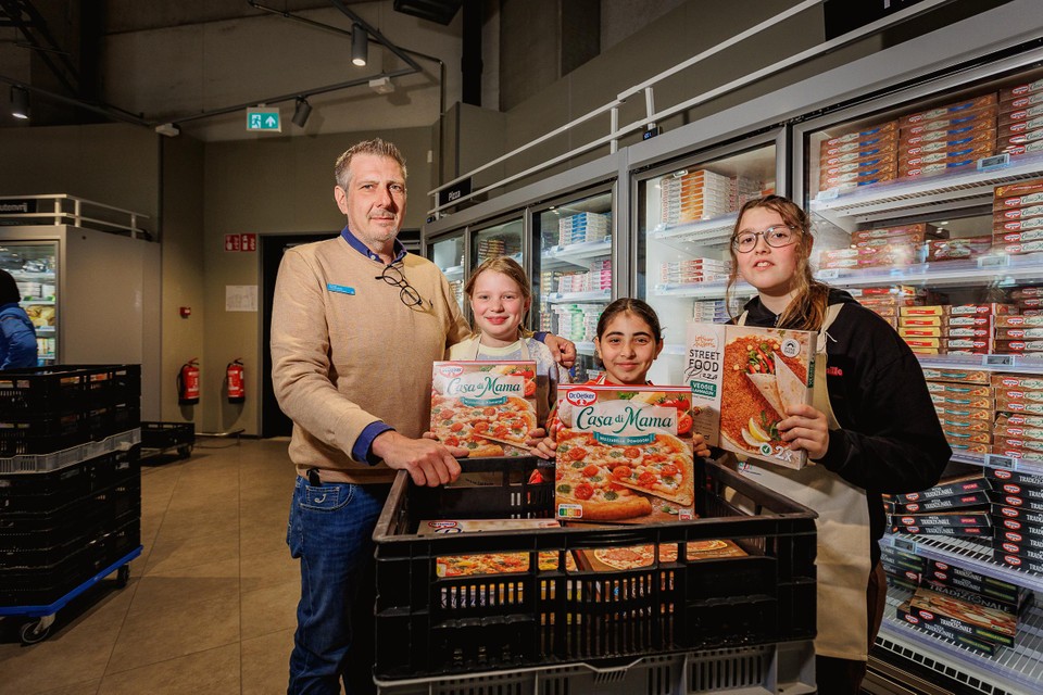 Lisa, Fien en Lore vullen samen met winkelmanager Kristof Vande Walle de pizza’s aan.