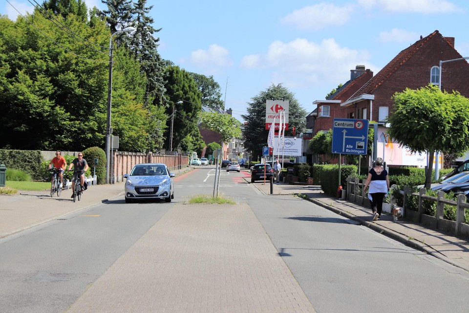 De Sint-Amandsesteenweg ter hoogte van de supermarkten, met links de kerkhofmuur die plaats maakt voor een haag.
