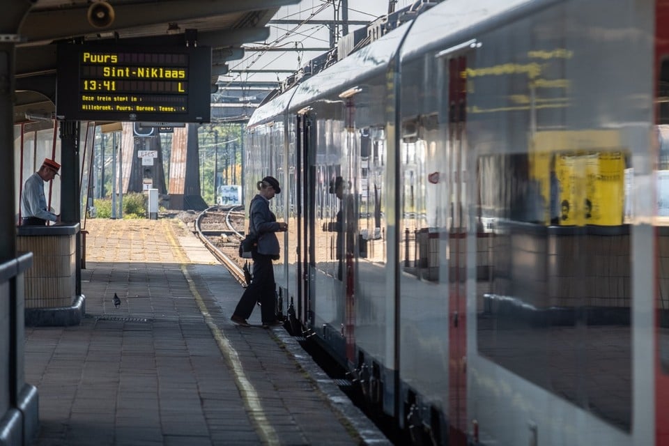 Een treinbegeleider stapt op de trein tussen Mechelen en Sint-Niklaas. 