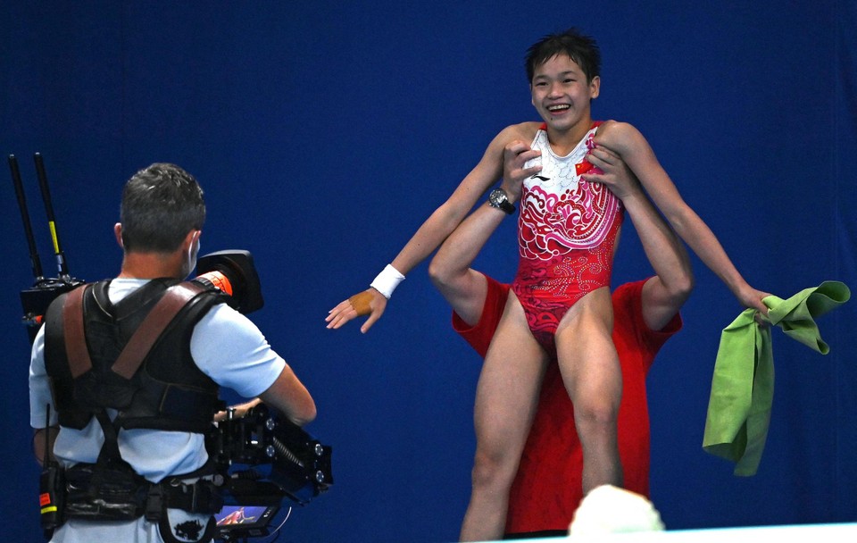 De amper 14-jarige Quan Hongchan wordt na drie quasi perfecte sprongen in de lucht gestoken door een van de Chinese coaches.