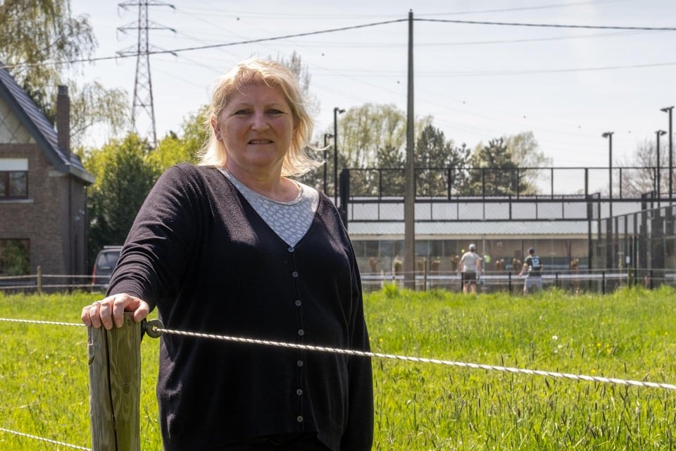 Ria Vertommen voor haar huis en de gloednieuwe padelvelden, die amper drie meter naast haar woning liggen.