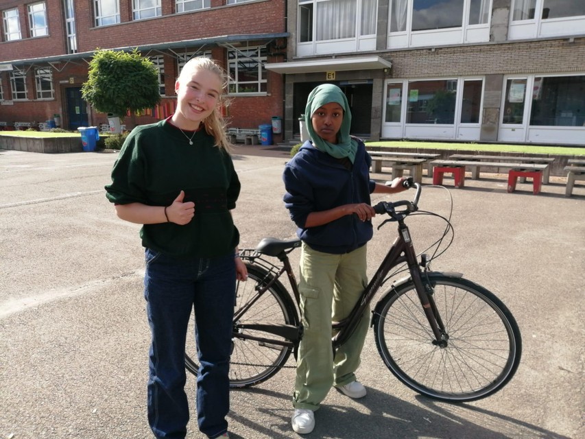 Een zesdejaars helpt een leerlinge uit de onthaalklas voor anderstalige nieuwkomers (OKAN) te leren fietsen.