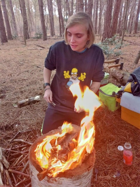 Emma maakt een vuurtje, onder toezicht van haar begeleiders van Studijo Bos.