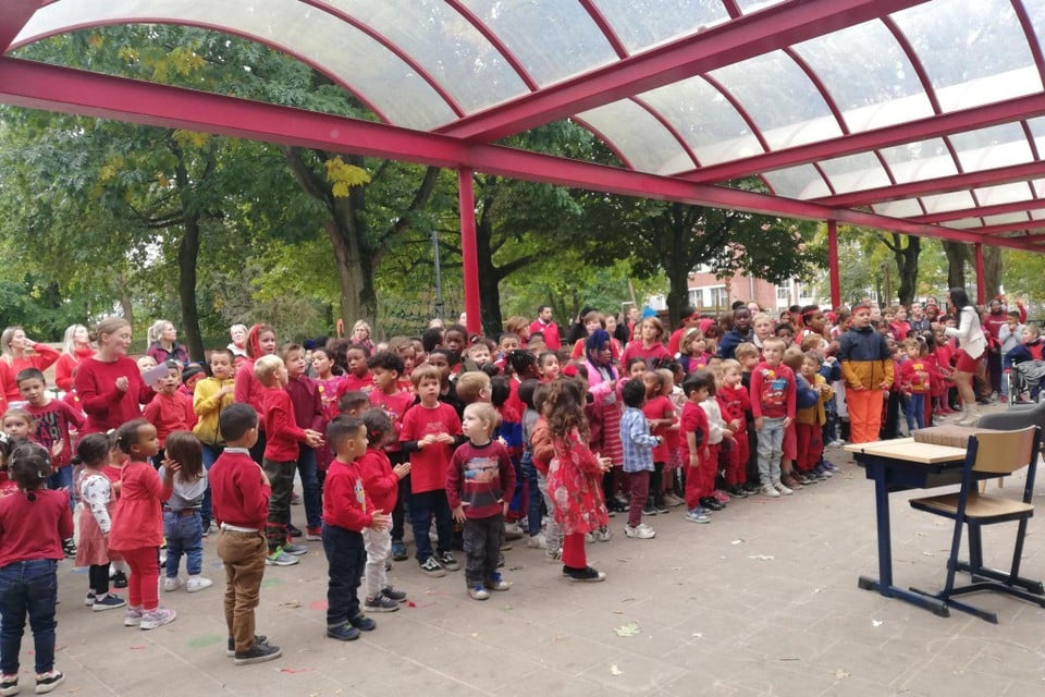 De leerlingen dragen rode outfits als verwijzing naar het schoollogo. 