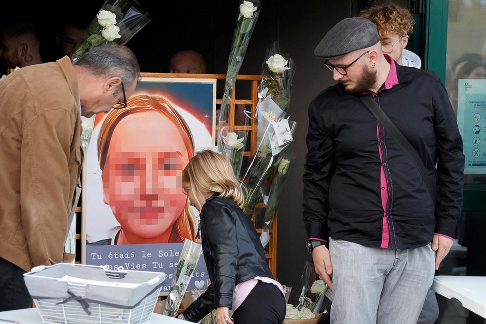 Een meisje legt bloemen bij het portret van Lola, onder het oog van Jordan (rechts), een broer van het slachtoffer. 