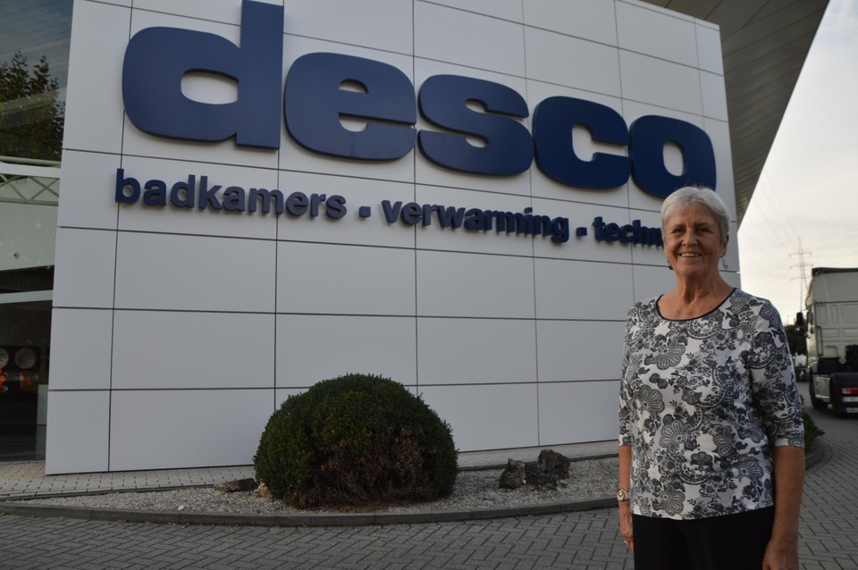 Denise bij de hoofdzetel van Desco, op 800 meter van haar deur. Ze komt te voet naar het werk.