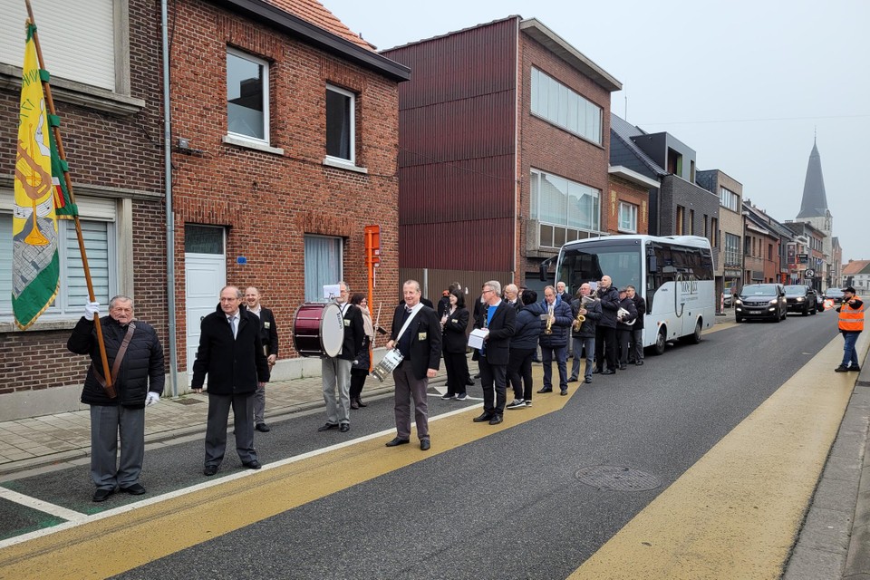 De Reetse harmonie Sint Cecilia met achter de muzikanten de klaarstaande autobus. 